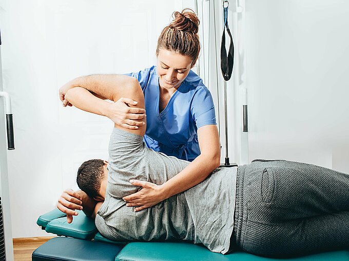 Physiotherapist treatment patient. She holding patient's hand, shoulder joint treatment
